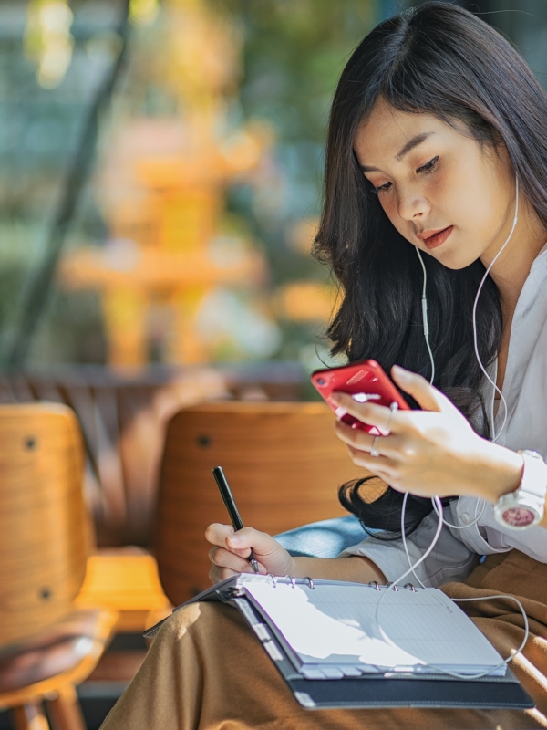 A picture of a young Asian lady looking at her mobile phone whilst seated at a cafe