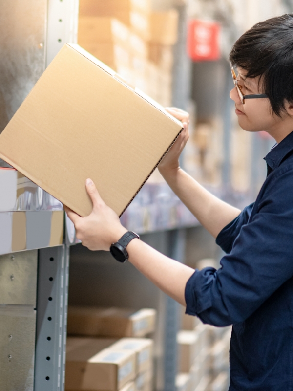Young Asian student packing shelves in a warehouse